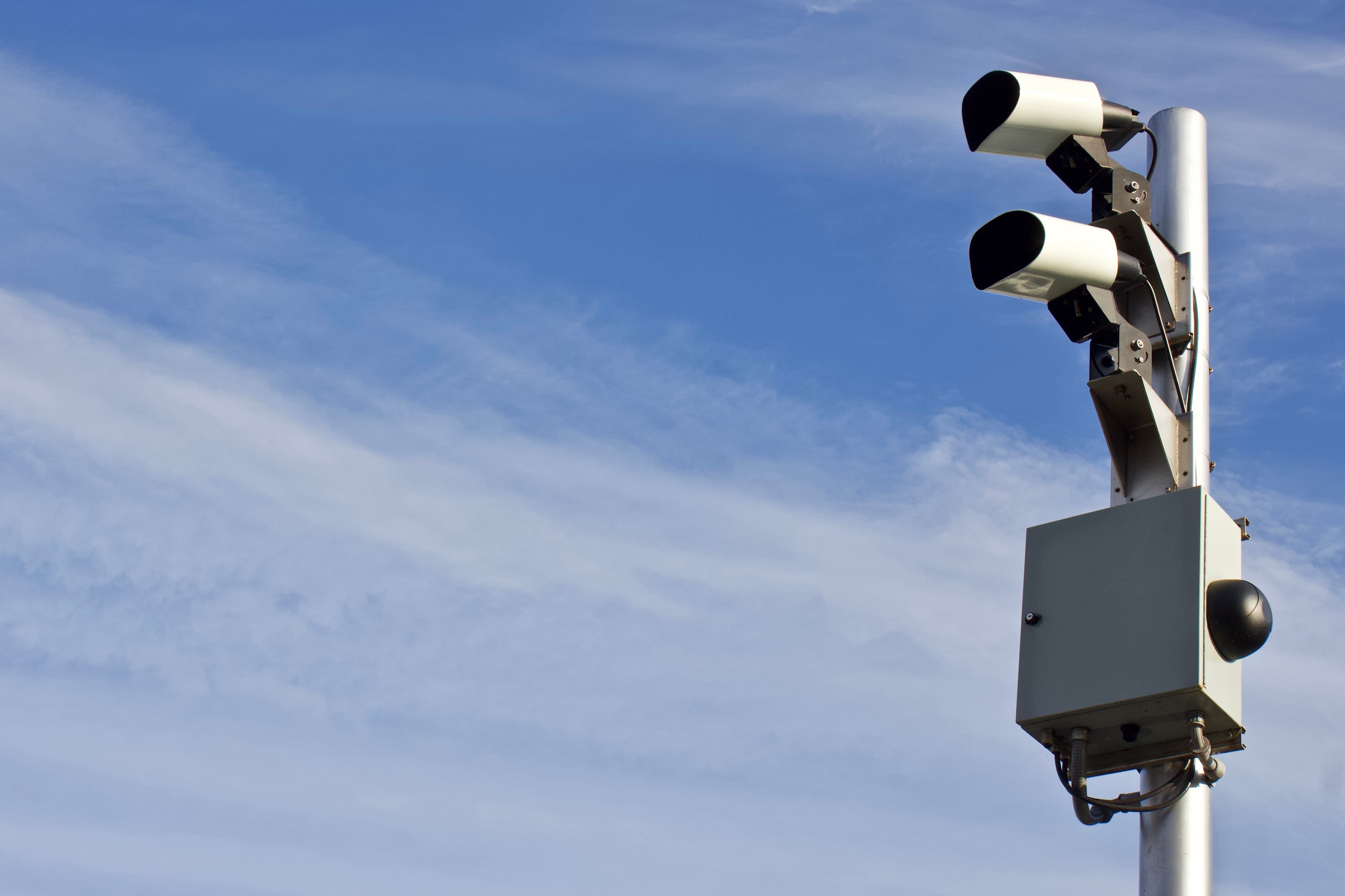 An automated license plate reader camera under the blue sky.