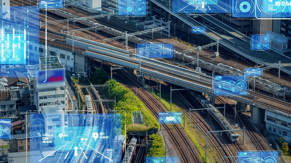 Aerial view of a railway junction with overlay graphics demonstrating Collision Avoidance Systems and telematics technology, including data on train speeds and track information.