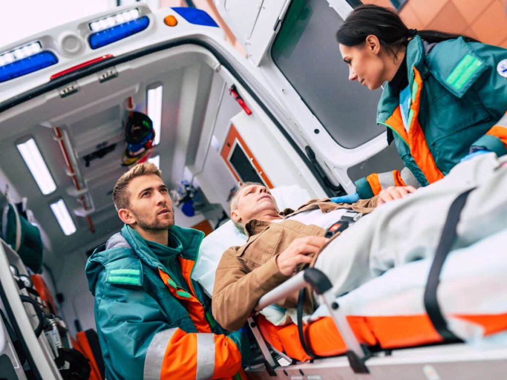 Emergency responders assisting an injured person beside an ambulance equipped with an onboard computer for reliable fleet connectivity